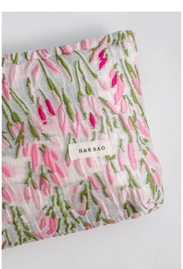 Close-up of the jacquard tulip fabric texture and stitched brand logo on a makeup bag