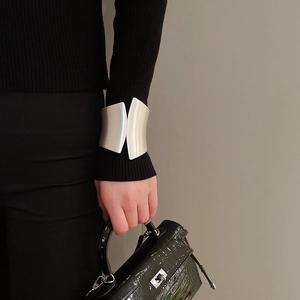 Detail view of a wide irregular silver cuff bracelet styled with a chic black outfit