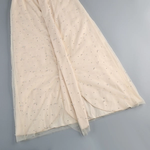 Dettaglio del tessuto in tulle color albicocca a strati con decorazioni in perle bianche