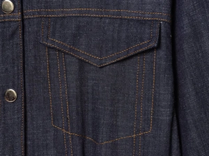Close-up of dark blue denim fabric with metal buttons and contrast orange stitching