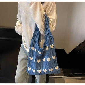 Detalle del bolso de punto azul con diseño de corazones blancos y tejido calado