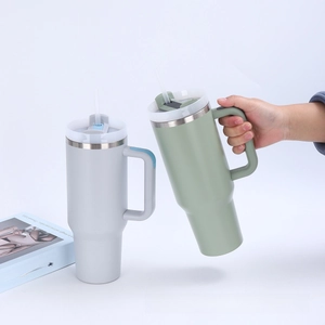 Close-up of matte 40oz insulated tumblers in light grey and sage green with ergonomic handles