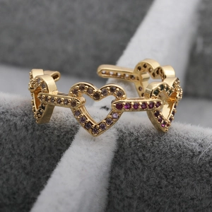 Macro detail of gold-plated open ring featuring purple and pink micro-pave heart links