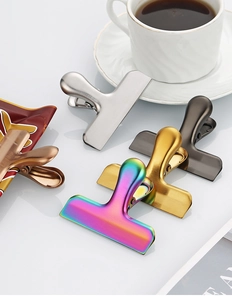 Close-up of T-shaped stainless steel food clips in silver, gold, black, and rainbow colors