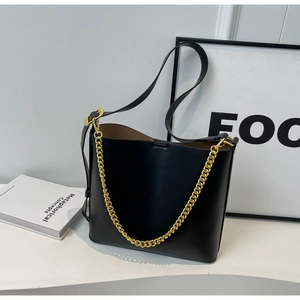 Detail of black leather bucket bag with gold chain strap and minimalist design features