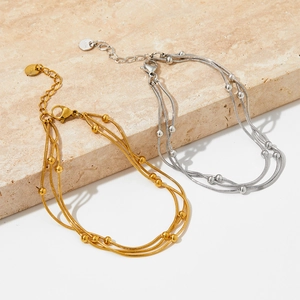 Détail de bracelets perlés multicouches en or et argent sur une surface en marbre