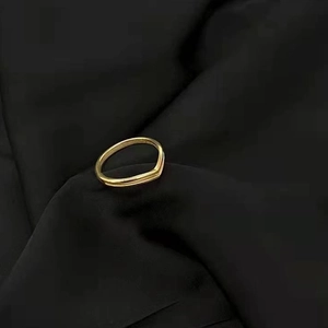 Detailed close-up of a double-layer V-shaped 18K gold titanium ring on black silk