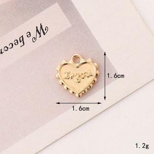 Detailed view of heart-shaped gold pendant with I Love You engraving and beaded edges