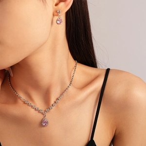 Detail of elegant silver jewelry set featuring pink teardrop gems and zircon stones