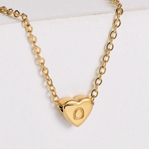 Macro view of a 18k gold-plated heart pendant with engraved letter O and fine link chain