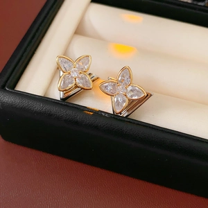 Macro view of gold and silver four-leaf clover earrings with zircon in a black gift box