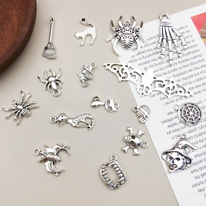 Flat lay of vintage silver Halloween charms including spiders and bats on a beige desk