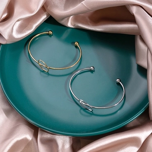 Detailed view of minimalist gold and silver knot bracelets on elegant satin fabric