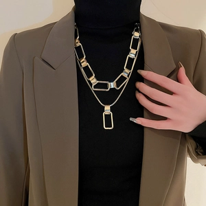 Close-up of a double-layered gold chain necklace with a sleek rectangular pendant