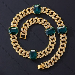 Dettaglio delle pietre verde smeraldo sulla collana a maglie cubane in oro lucido