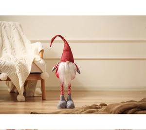 Detail of Christmas gnome with red knit hat and long faux fur beard in cozy home setting