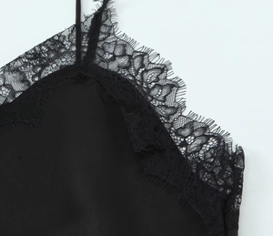 Detailed close-up of fine eyelash lace trim on a black silk-textured camisole dress