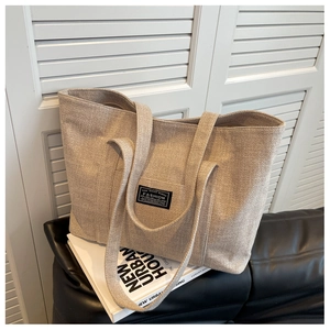 Close-up of beige canvas tote bag with fashion label on white artistic books
