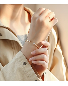 Detail of 18K gold plated cuff bracelet and V-ring set with clear cubic zirconia on wrist