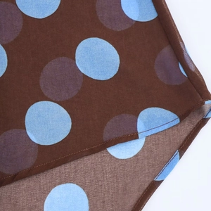 Macro detail of brown chiffon hem with large blue and purple polka dots and fine stitching