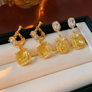Detail of 18K gold plated square yellow gem earrings with white zircon halo in jewelry box