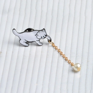 Cute white enamel cat brooch with golden chain and pearl pendant on striped fabric