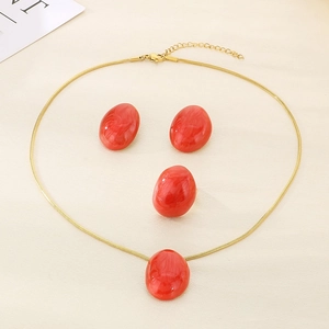 Flat lay of gold snake bone jewelry set with red oval enamel pendants and marble texture