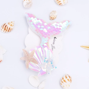 Close-up of sequined mermaid tail hair clip with holographic shell and glitter stars
