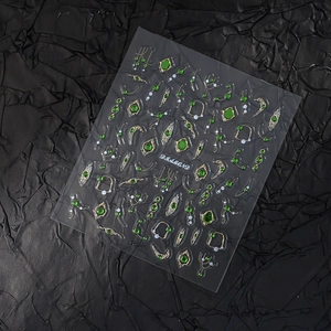 Detail shot of luxury emerald gemstone nail stickers with gold embossed lace and pearls