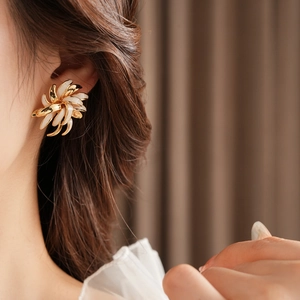 Detailed view of vintage gold plated daisy earrings with white enamel petals on model