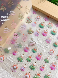 Macro detail of 3D embossed Christmas tree and snowflake nail art stickers with gold foil