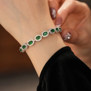 Détail d'un bracelet en argent avec pierres vertes ovales sur le poignet d'un mannequin