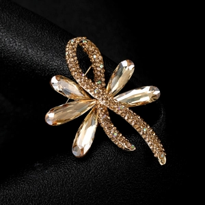 Macro shot of gold-tone bow brooch with clear and champagne rhinestones on black leather