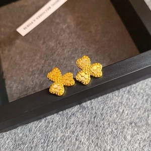 Macro shot of gold clover stud earrings with textured honeycomb finish and 925 silver needles