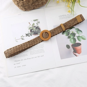 Close-up of a brown woven waist belt with a round wooden buckle on a magazine background