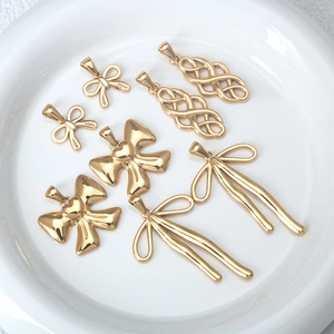Golden stainless steel bow and knot pendants collection on a white plate for DIY jewelry