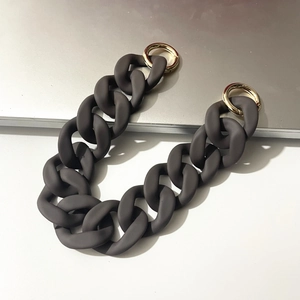 Macro detail of matte dark grey resin chain strap with gold metal buckles on desk