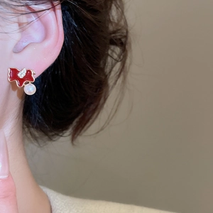 Close-up of red bow stud earring with pearl drop and zircon detail on model ear