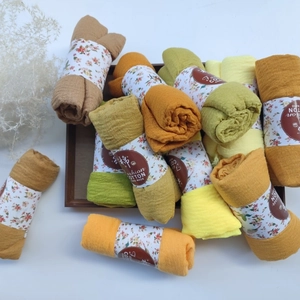 Macro detail of wrinkled cotton viscose scarves in warm colors with floral packaging