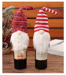 Close-up of knit Christmas gnome wine bottle covers with white faux fur beards and noses