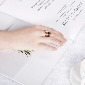 Detail of three-layer rose gold Roman numeral ring on hand with elegant fur background
