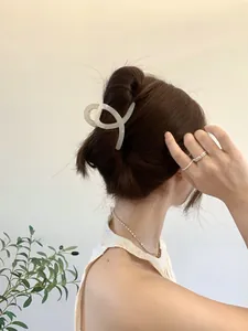 Vue détaillée d'une pince à cheveux crème au design croisé torsadé portée sur l'arrière