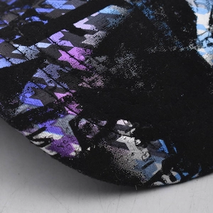 Close-up of abstract purple tie-dye patterns and star prints on fabric baseball cap