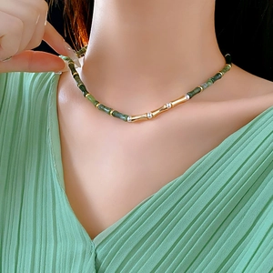 Close-up of bamboo-style gold chain with green jade beads on a model's neck