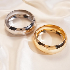 Close-up of polished gold and silver metal bangles on elegant cream satin fabric