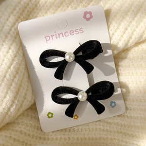 Detail of black velvet bow hair clips with central pearl on a princess display card