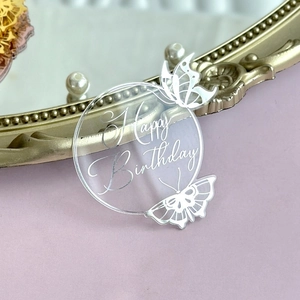 Macro view of transparent acrylic Happy Birthday cake topper with hollow butterfly design