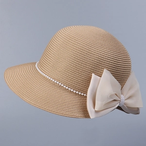 Vue détaillée d'un chapeau de paille pour femme avec nœud en satin et chaîne de perles