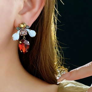 Close-up of vintage baroque style earrings with colorful gemstones worn on a model's ear