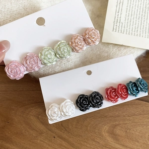 Detail of rose flower stud earrings with pearl luster on a soft fabric background